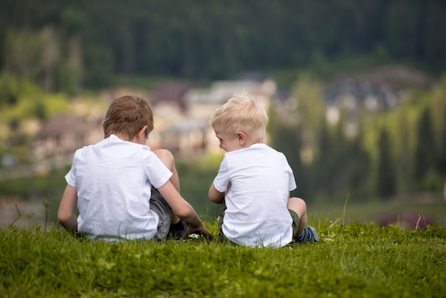 Dois meninos sentam-se numa colina e se divertem.