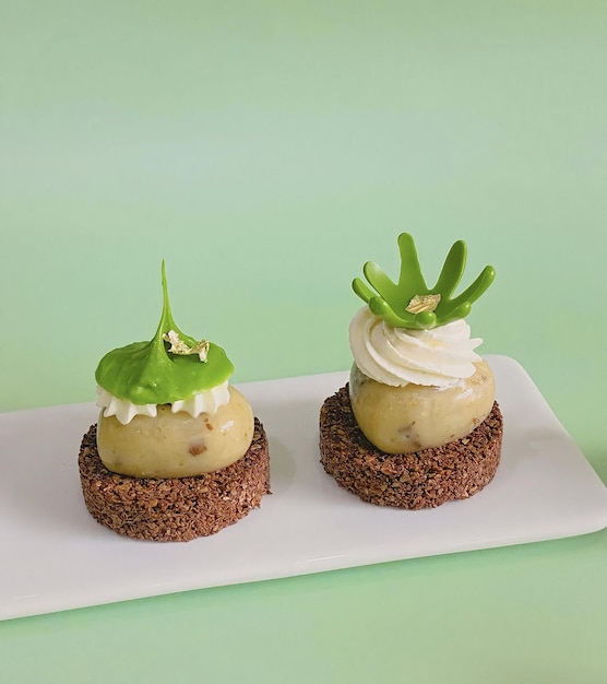 Dois mini bolos com folhas verdes no topo estão em um prato branco.