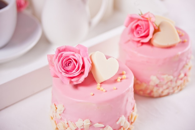 Foto dois mini bolos com rosas em uma mesa branca. conceito de jantar romântico