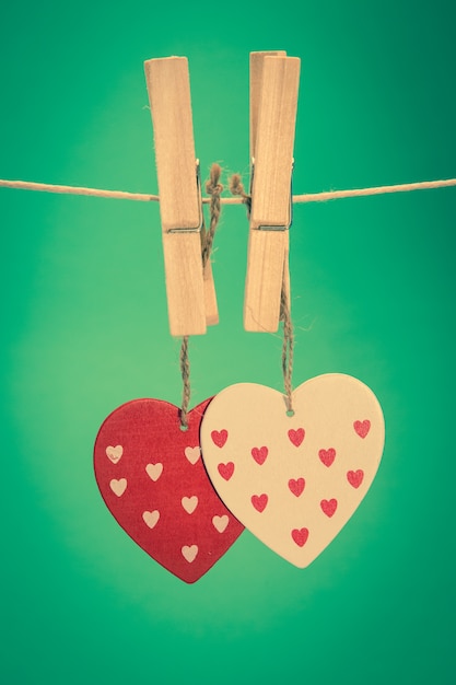 Dois ornamentos de coração que penduram de cavilhas em uma linha