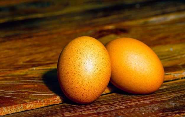 Dois ovos de galinha marrons na velha mesa de teca, em foco raso