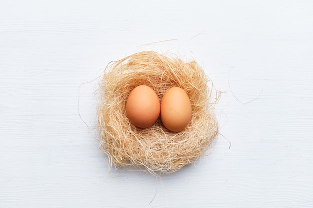 Dois ovos em um ninho de grama seca e galhos em uma mesa de madeira. Conceito de Páscoa feliz.