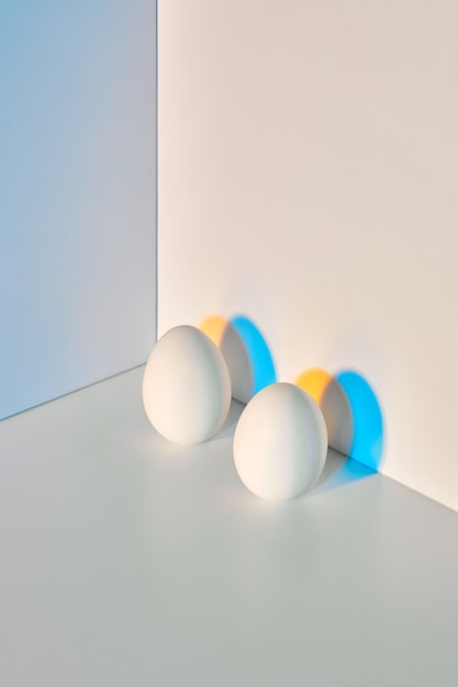 Dois ovos são apresentados em um fundo bege azul-acinzentado triplo com um reflexo de sombras e espaço