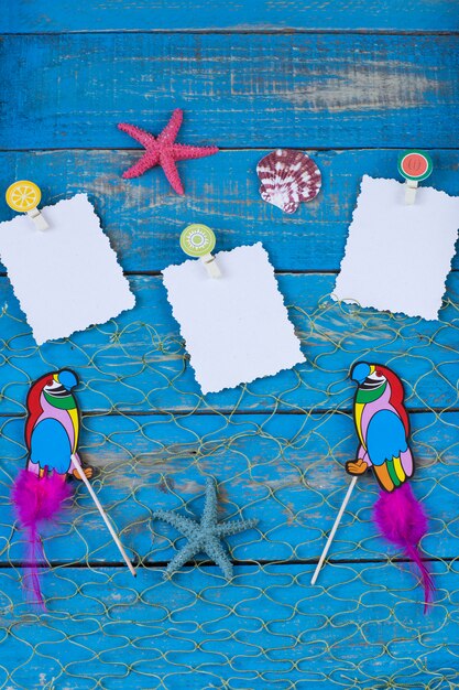 Foto dois papagaios, estrelas do mar, conchas e papel de nota sobre um fundo azul de madeira