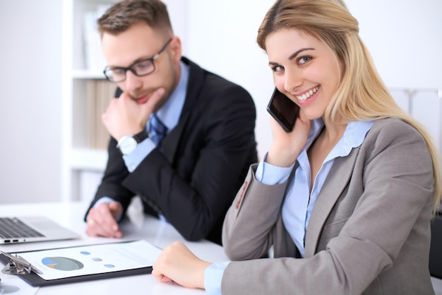 Dois parceiros de negócios bem-sucedidos trabalhando em reunião no escritório Concentre-se na loira enquanto fala por telefone