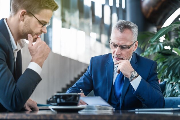 Dois parceiros de negócios fazendo anotações e discutindo algum projeto no café