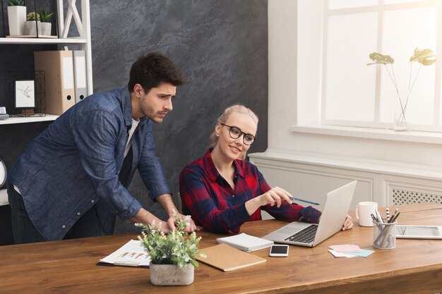 Dois parceiros de negócios trabalhando em um escritório moderno. Dois colegas de trabalho discutindo um novo projeto enquanto trabalhava no laptop, copie o espaço