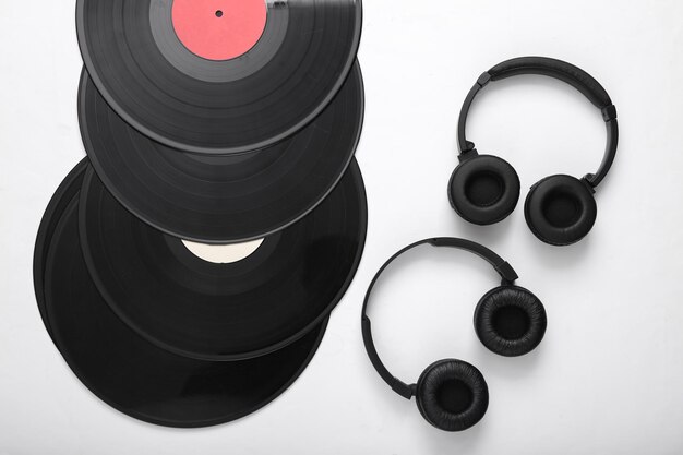 Dois pares de fones de ouvido estéreo pretos e discos de vinil em fundo branco