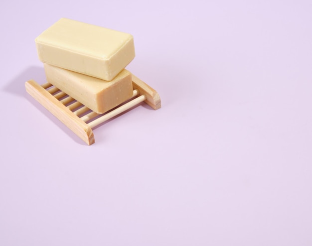 Dois pedaços naturais de sabão estão sobre uma saboneteira de madeira em forma de treliça Acessórios para spa Copiar espaço para texto