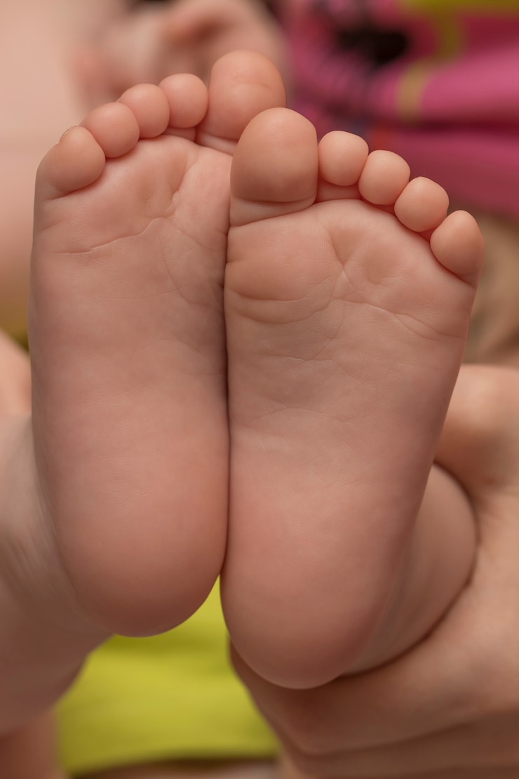 Dois pés de bebê nas mãos da mãe, close-up