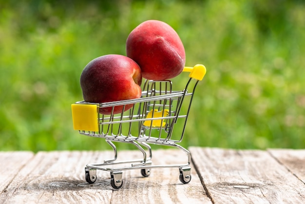 Dois pêssegos maduros em um pequeno carrinho de compras.