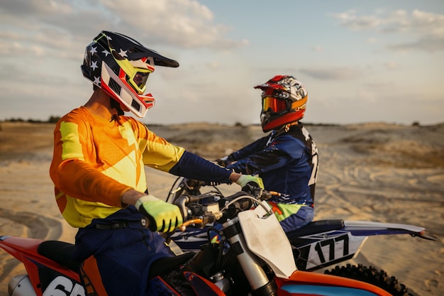 Foto dois pilotos de motocross mx conversando antes das corridas de velocidade. busca recreativa de esportes radicais