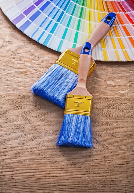 Dois pincéis de pintura e paleta de cores na placa de madeira