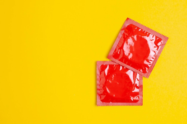 Dois preservativos vermelhos estão sobre um fundo amarelo o conceito de sexo seguro