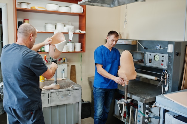 Dois protesistas fazendo próteses de perna enquanto trabalhavam no laboratório.