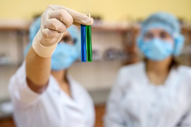 Dois químicos em laboratório examinando frasco com substância azul