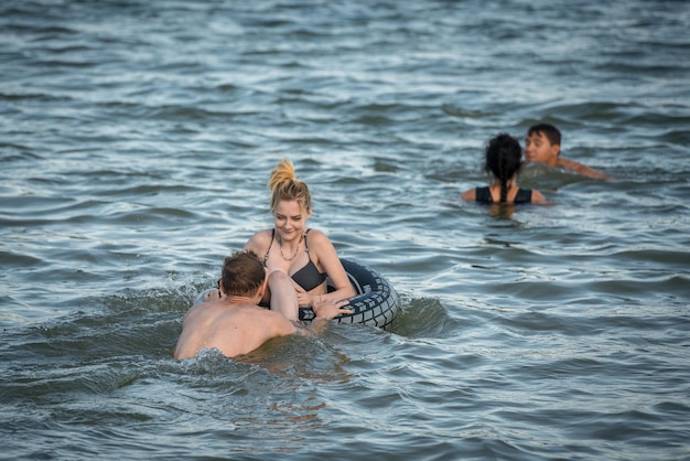 Dois rapazes e uma garota estão nadando no lago