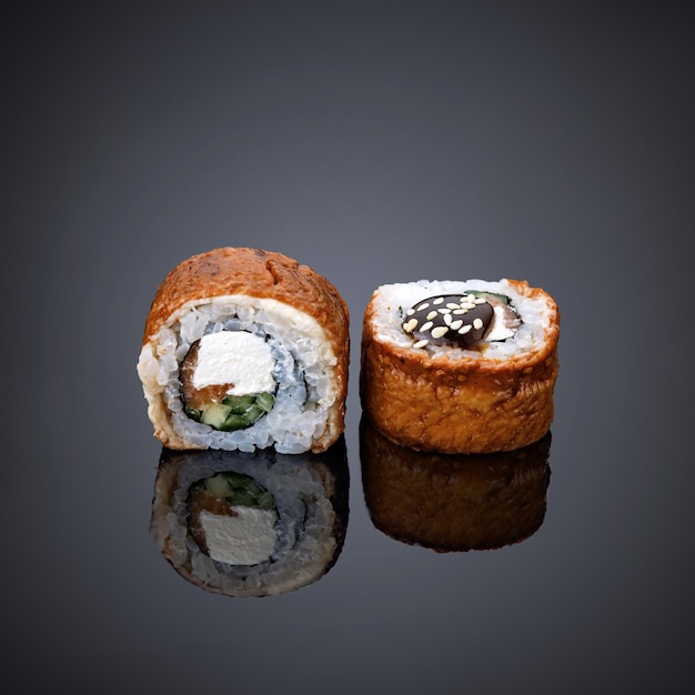 Dois rolos de sushi estão em um fundo preto com fundo preto.