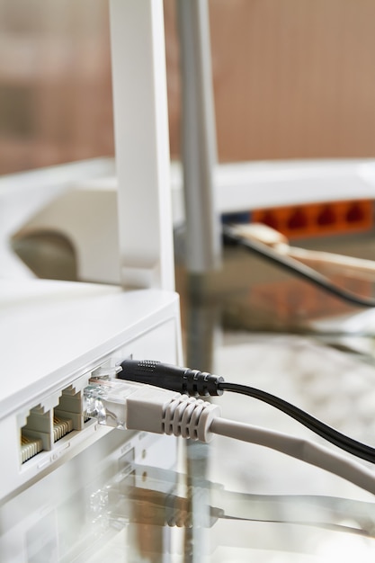 Dois roteadores sem fio brancos em uma mesa de vidro conectados por cabos à Internet