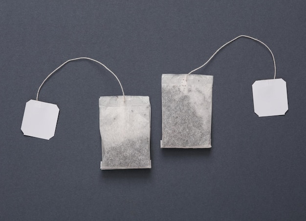 Dois sacos de chá com rótulos brancos em branco em um fundo cinza escuro