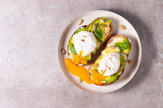 Foto dois sanduíches abertos de abacate com ovo. conceito de ceto e dieta. comida de torrada saudável no café da manhã.