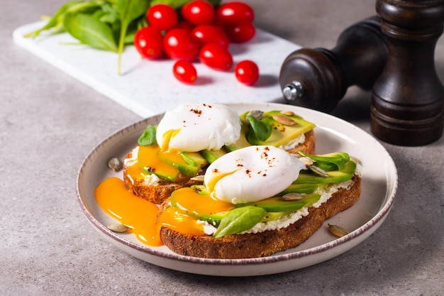 Dois sanduíches abertos de abacate com ovo. Conceito de ceto e dieta. Comida de torrada saudável no café da manhã.