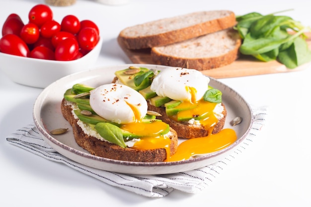 Dois sanduíches abertos de abacate com ovo. Conceito de ceto e dieta. Comida de torrada saudável no café da manhã.