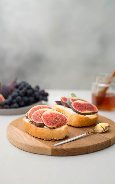 Dois sanduíches com mel de queijo creme de figos frescos e uvas na luz de fundo