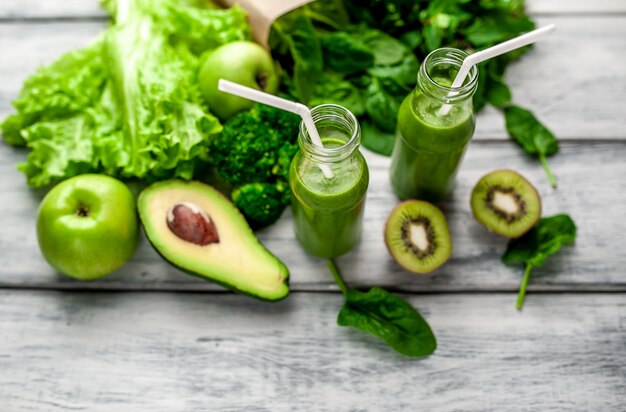 dois smoothie com legumes, abacate, maçã, kiwi em um fundo de madeira. nutrição esportiva