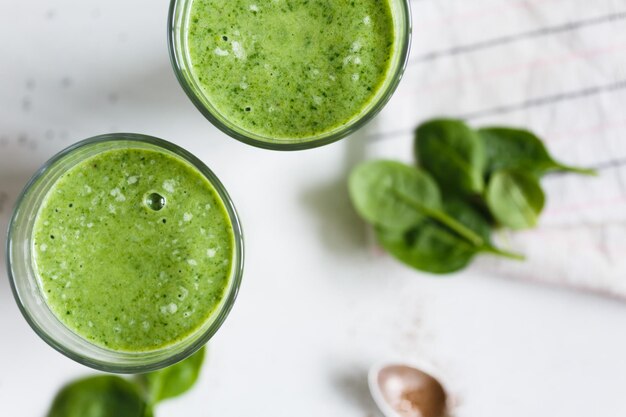 Dois smoothie verde com ervas frescas de banana e espinafre na vista superior de fundo