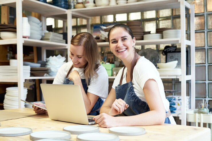 Foto dois sorrindo empresário feminino com laptop na oficina de artesão.