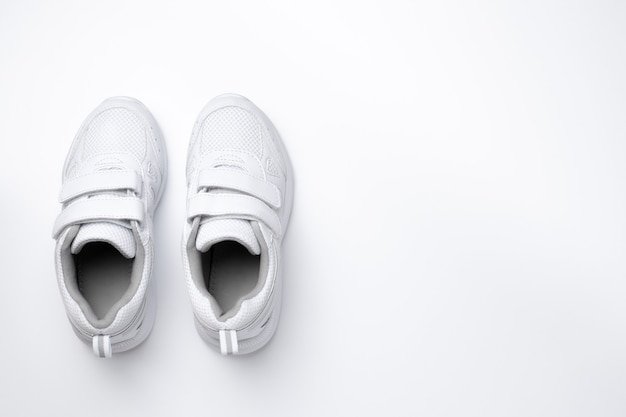 Dois tênis femininos brancos com fechos de velcro isolados em um fundo branco.