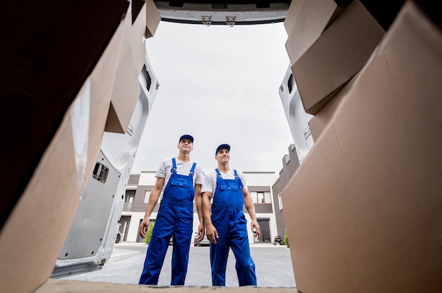 Dois trabalhadores da empresa de mudanças descarregando caixas do microônibus