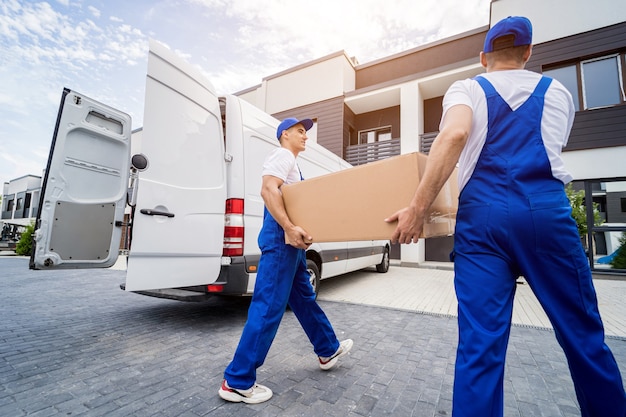 Dois trabalhadores da empresa de mudanças descarregando caixas e móveis do microônibus