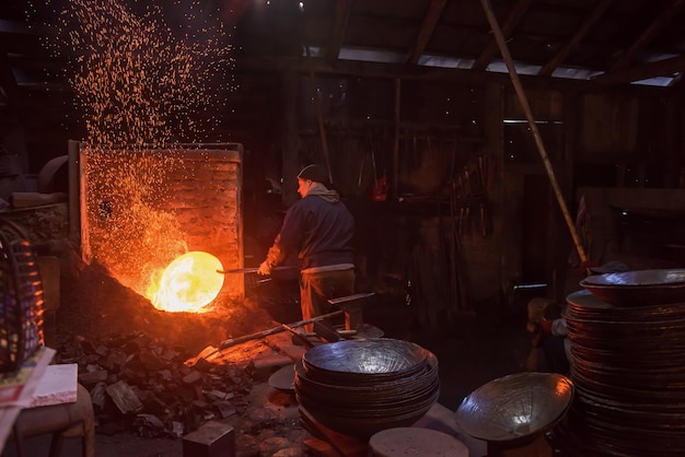 dois trabalhadores de ferreiro tradicionais brutais trabalhando juntos com um ferro em brasa usando martelo mecânico na oficina Retrato de uma profissão