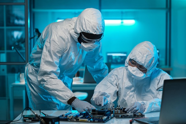 Dois trabalhadores de laboratório contemporâneos em macacões de proteção