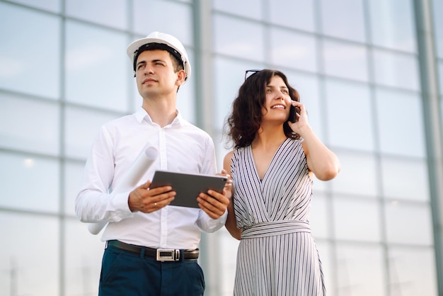 Dois trabalhadores em um capacete em um objeto de trabalho discutem questões de trabalho