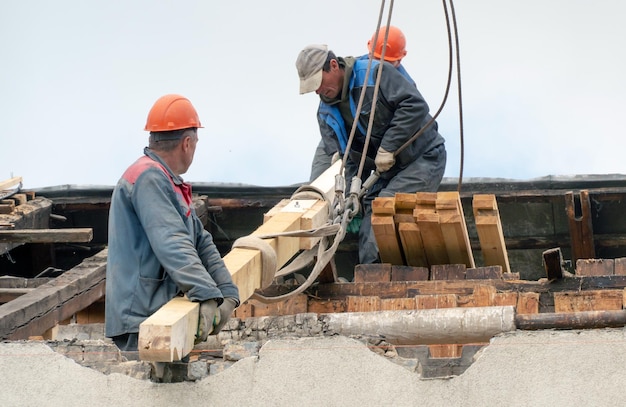 Dois trabalhadores estão reparando o telhado de um edifício antigo Reparação da substituição do telhado de tetos e vigas de madeira instalação de novas telhas vermelhas