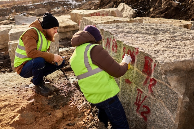 Dois trabalhadores marcando blocos de granito