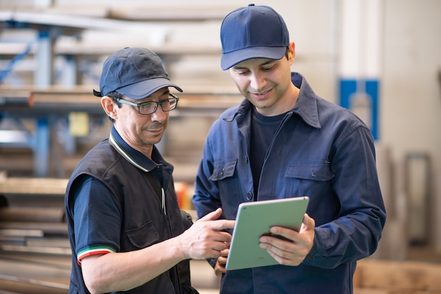 Dois trabalhadores usando um tablet em uma fábrica moderna