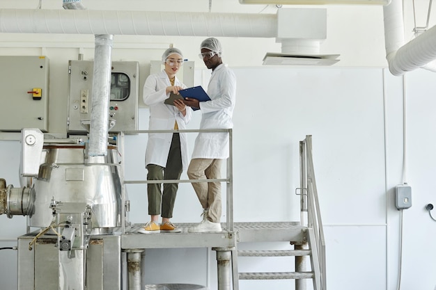 Dois trabalhadores vestindo casacos de laboratório na oficina da fábrica