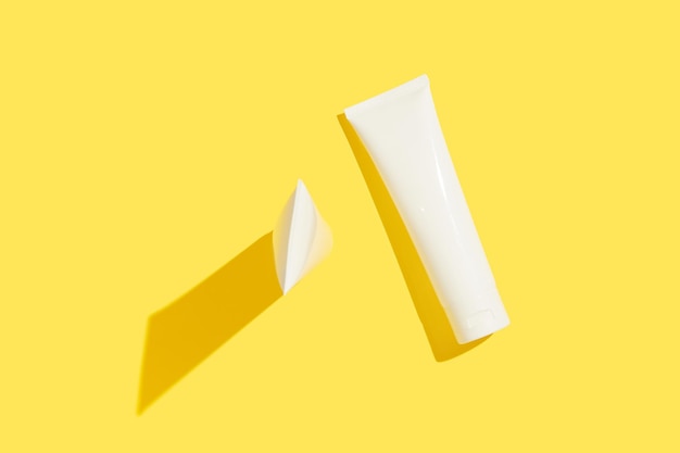 Foto dois tubos de creme pop contra uma tela amarela radiante banhada em luz ousada radiante cuidado da pele