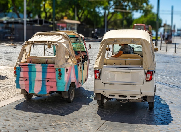 Foto dois tuk tuks turísticos de três rodas piaggio ape calessino 200 estacionados numa rua de paralelepípedos em lisboa