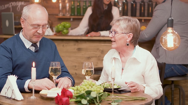 Dois velhos amigos na casa dos 60 anos conversando sobre o que têm feito ultimamente durante um jantar em um restaurante