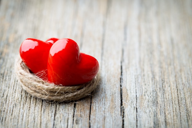Dois vermelhos em forma de coração sobre um fundo de madeira.