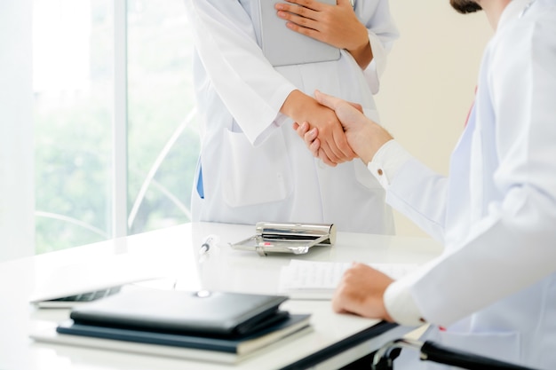 Doktor am Krankenhaus, das einem anderen Doktor Händedruck gibt, der Erfolg und Teamwork zeigt.