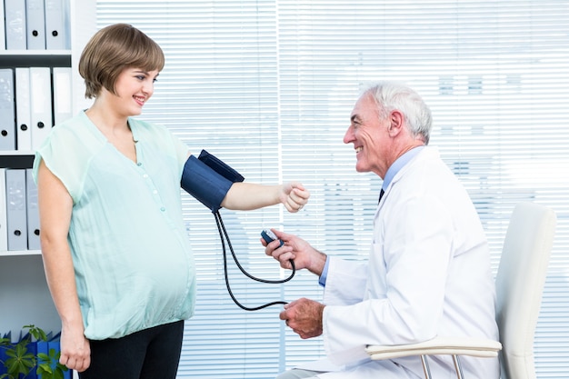 Doktor, der Blutdruck der schwangeren Frau überprüft