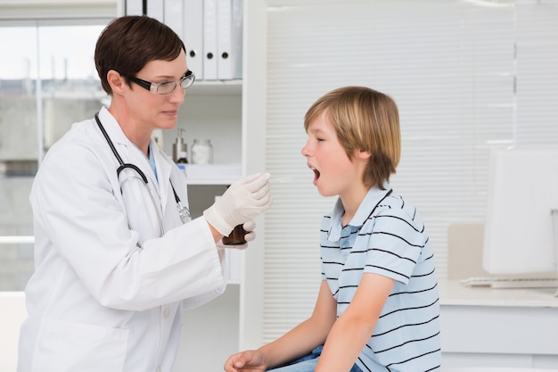 Doktor, der dem kleinen Jungen Sirup gibt