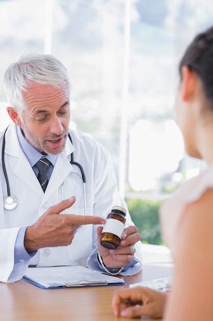 Doktor, der dem Patienten Flasche Pillen zeigt