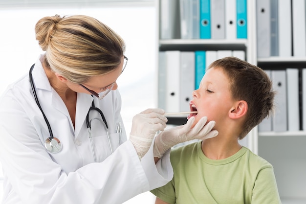 Doktor, der den Mund des Jungen untersucht